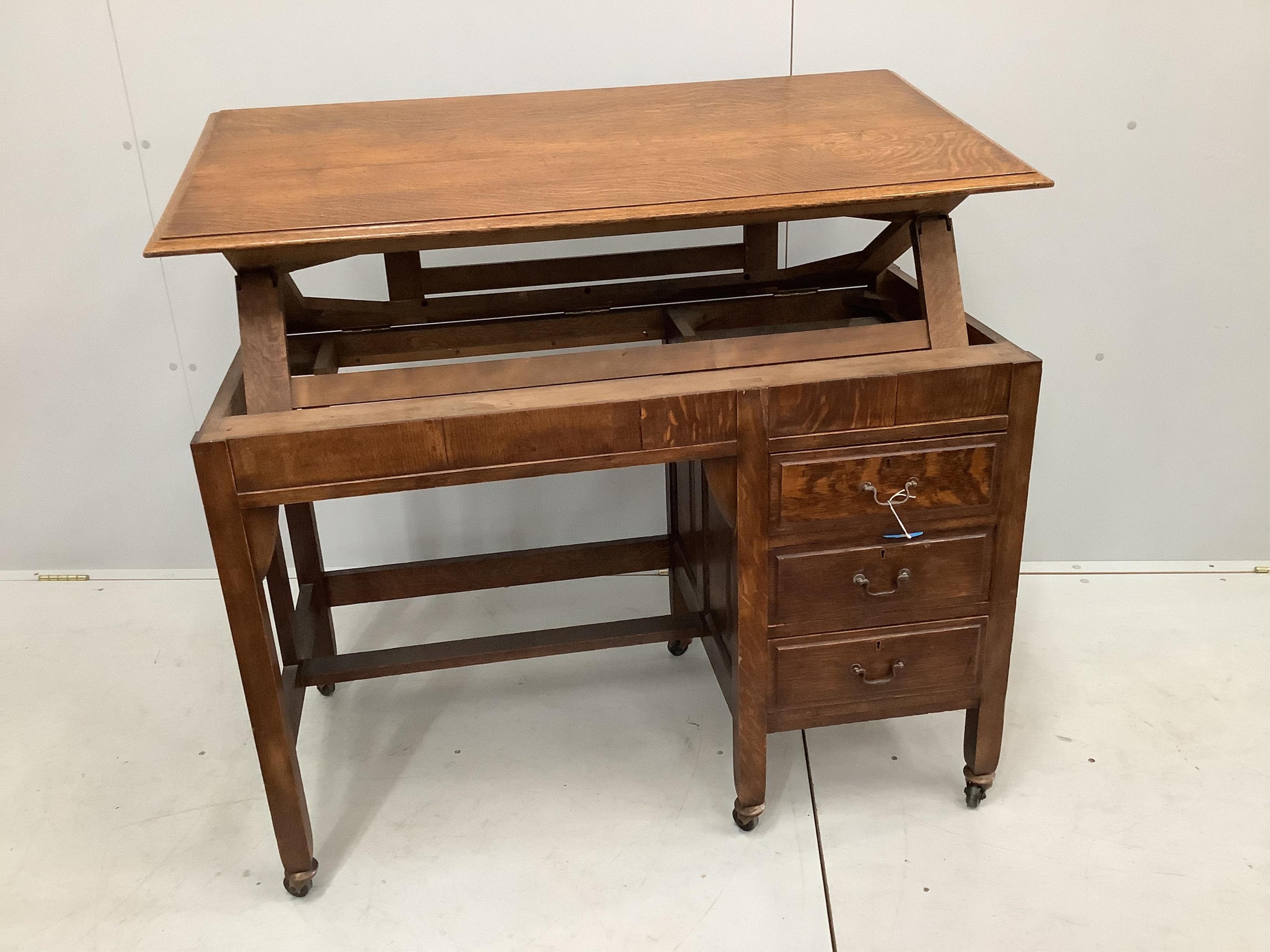 An Arts & Crafts metamorphic oak patent kneehole architect's desk, fitted three small side drawers, width 108cm, depth 56cm, height 72cm. Condition - fair